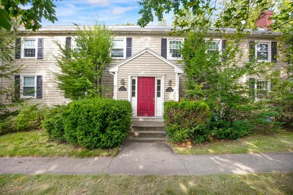 a view of front of house with a yard and potted plants