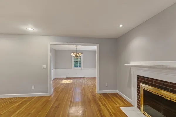 an empty room with wooden floor a fireplace and windows