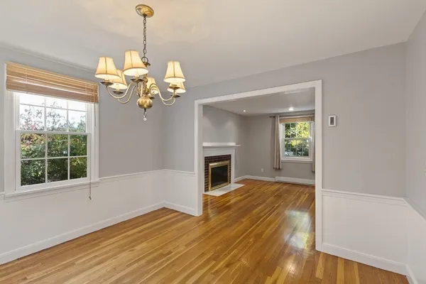 a view of a livingroom with a chandelier wooden floor fireplace and windows