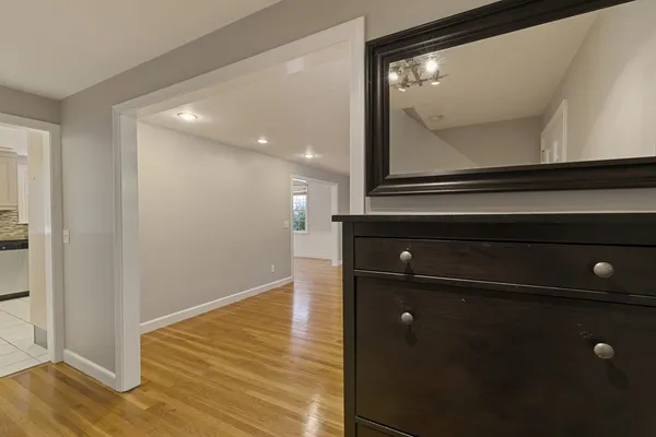 a view of a hallway with wooden floor and cabinet