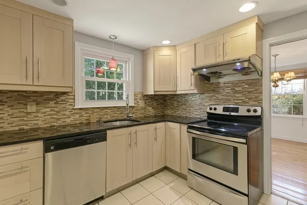 a kitchen with granite countertop white cabinets stainless steel appliances a sink and a window
