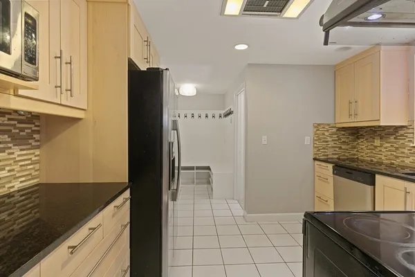 a kitchen with granite countertop a refrigerator and a stove top oven