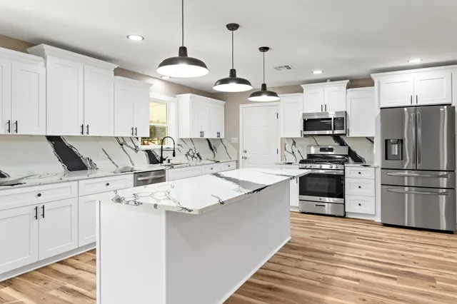 a kitchen with stainless steel appliances kitchen island a refrigerator sink and cabinets