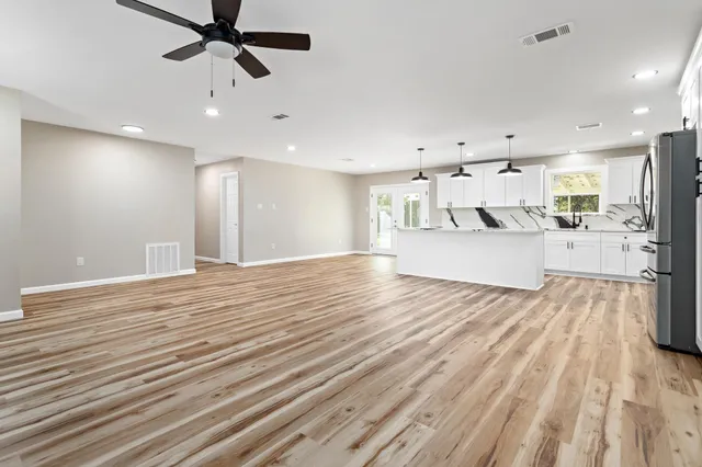 a view of a kitchen with kitchen island a sink wooden floor stainless steel appliances and a window