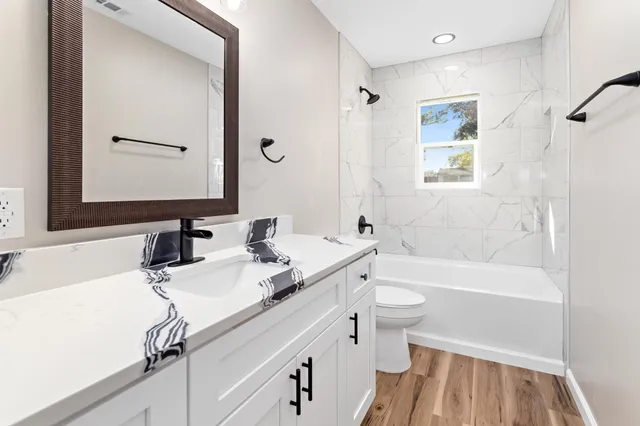 a bathroom with a sink a toilet a mirror and shower