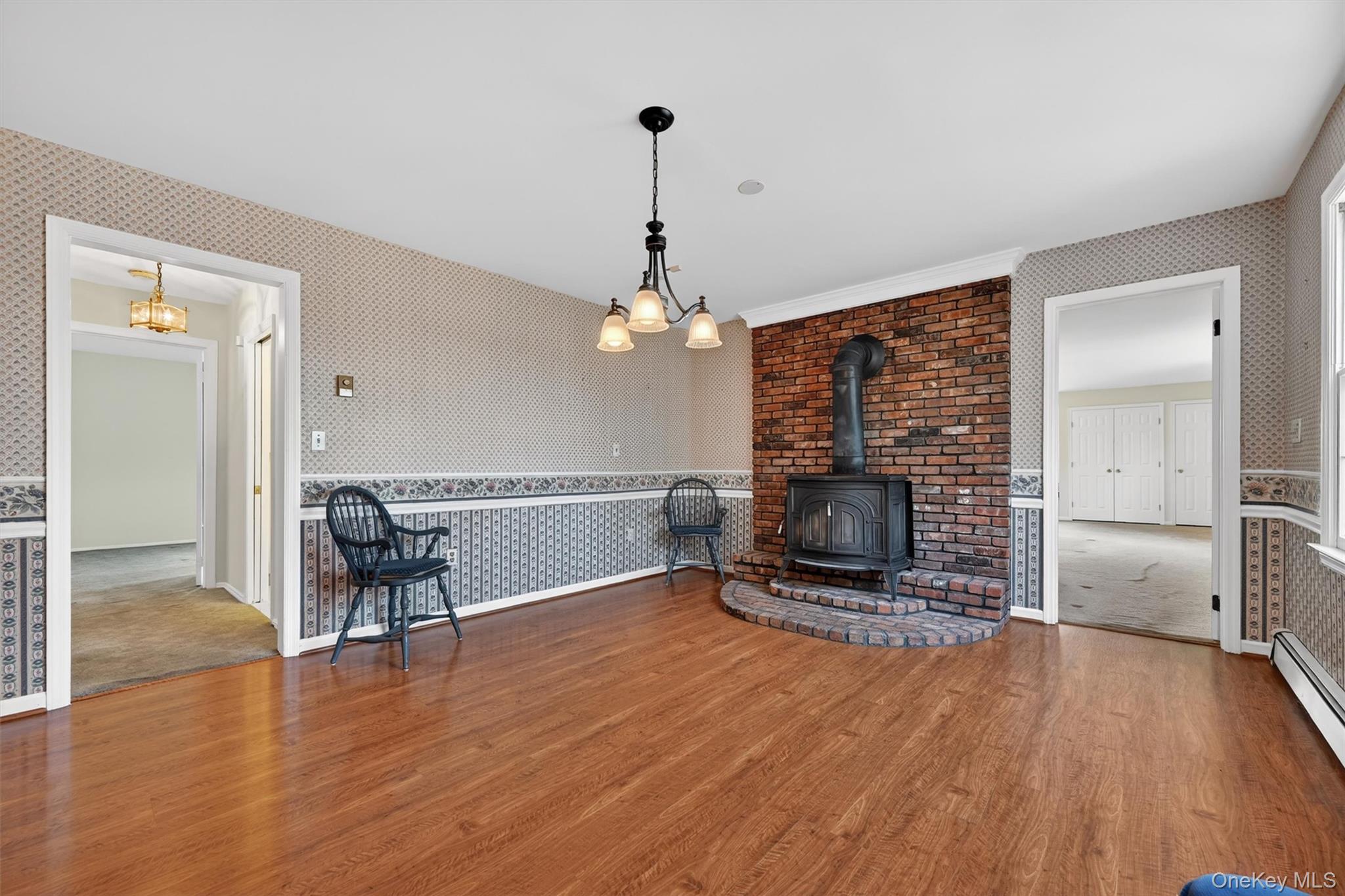 47 Still Road Westtown, NY 10998 - Photo 13 of 49 The dining area is part of the kitchen and features hardwood floors, a brick-faced wood-burning stove with a brick hearth, and a chandelier.