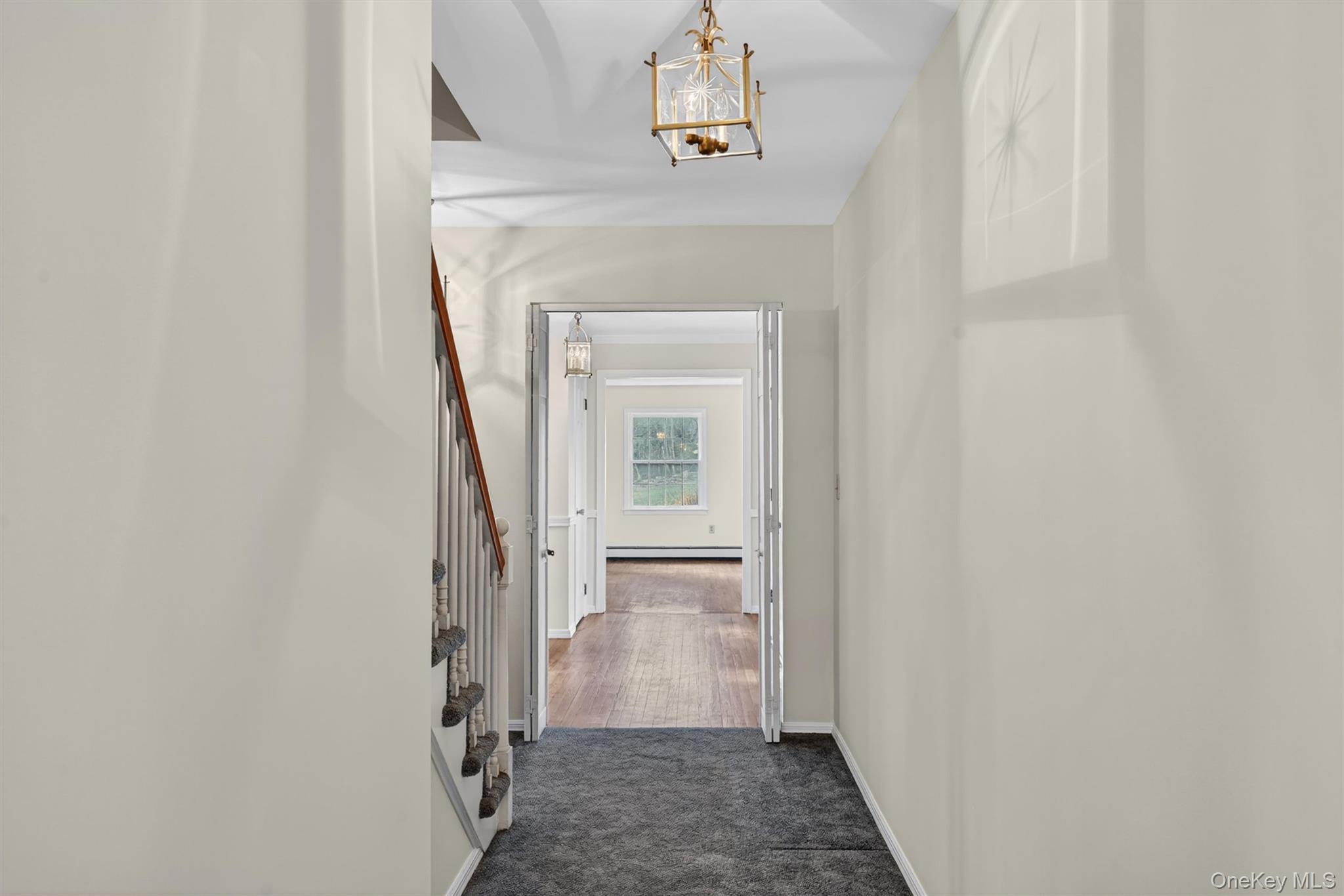 47 Still Road Westtown, NY 10998 - Photo 27 of 49 Hallway featuring a staircase with wooden handrails and white balusters, a ceiling-mounted light fixture, and carpeted flooring.