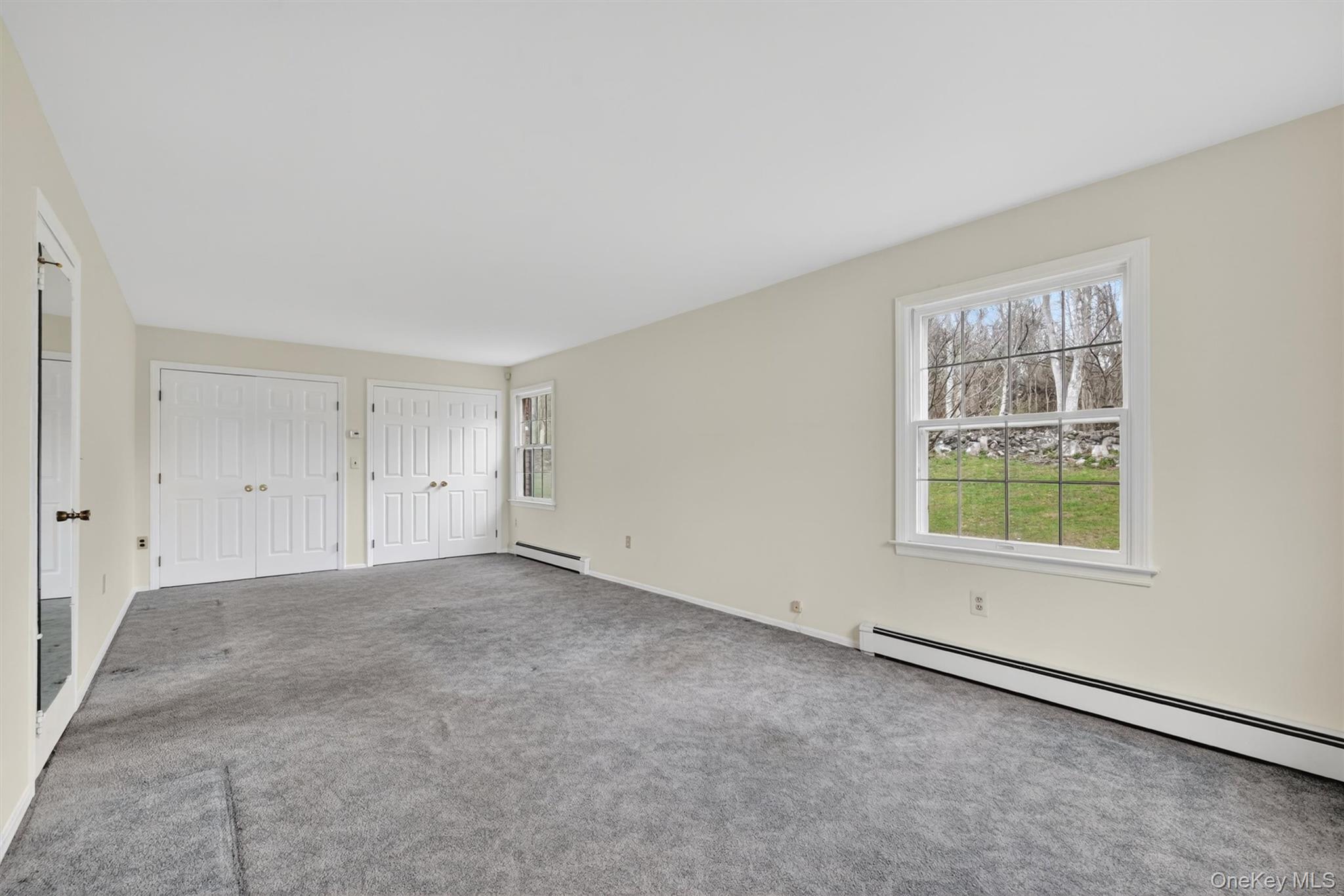 47 Still Road Westtown, NY 10998 - Photo 29 of 49 Primary bedroom - actual view. This spacious room featuring neutral-toned walls, grey carpeting, and two sets of bi-fold closet doors.