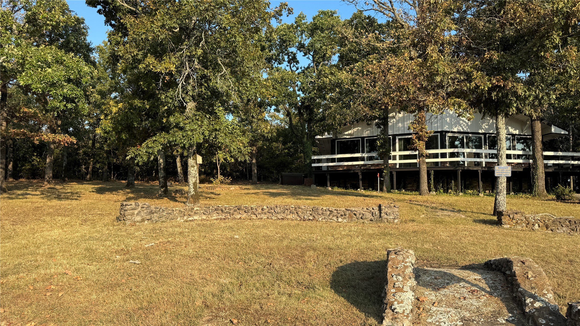96358 South 4531 Road Vian, OK 74962 - Photo 41 of 58 Elevated structure featuring extensive deck space with white railings and large windows, surrounded by mature trees and a manicured lawn