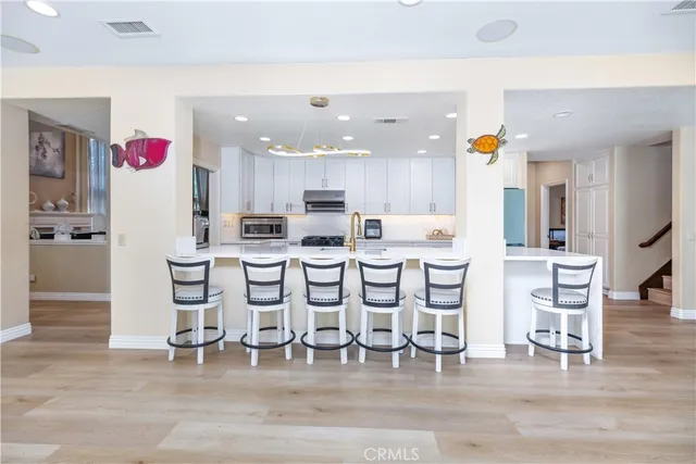 a open kitchen with stainless steel appliances kitchen island lots of white furniture a sink and a refrigerator