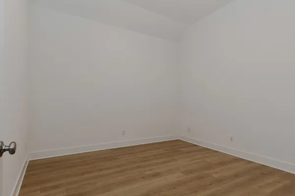 a view of an empty room with wooden floor and a ceiling fan