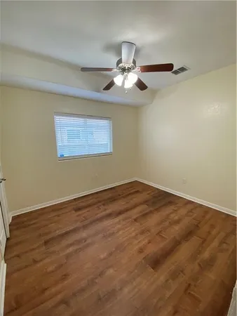 an empty room with wooden floor fan and windows