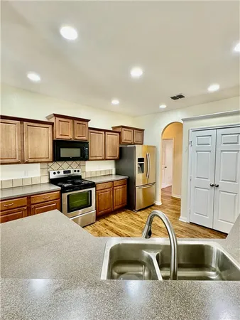 a kitchen with stainless steel appliances granite countertop a sink a stove and a refrigerator