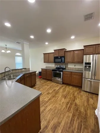 a large kitchen with a large counter top stainless steel appliances and cabinets