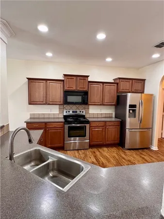 a kitchen with stainless steel appliances granite countertop a sink a stove and a refrigerator
