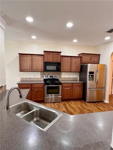 a kitchen with stainless steel appliances granite countertop a sink a stove and a refrigerator