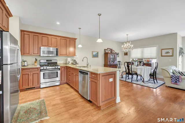 a kitchen with stainless steel appliances kitchen island granite countertop a stove top oven a sink a dining table and chairs