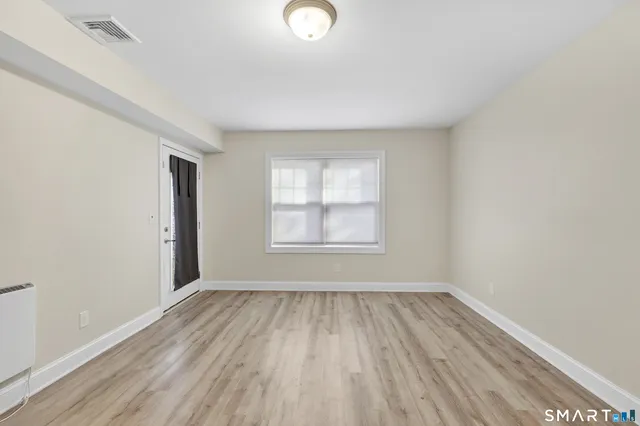 an empty room with wooden floor and windows