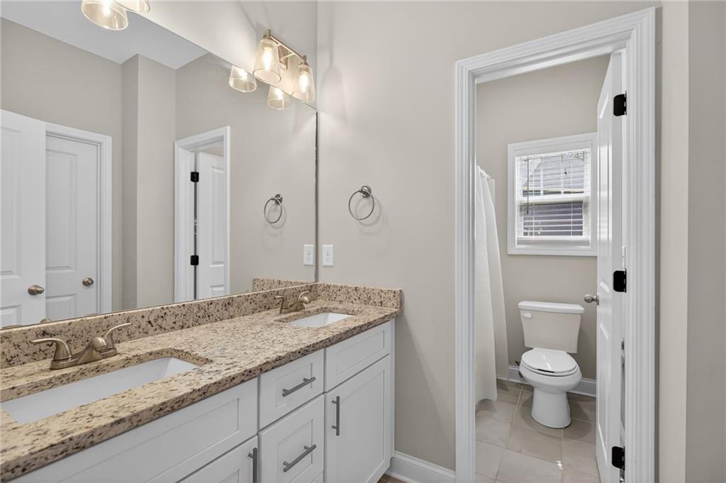 3156 Sweetbriar Drive Villa Rica, GA 30180 - Photo 33 of 45 a bathroom with a granite countertop toilet a sink and a mirror