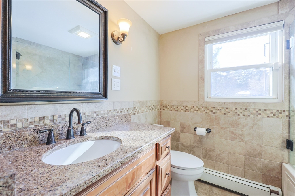 128 Salem Road Billerica, MA 01821 - Photo 20 of 42 a bathroom with a granite countertop sink a toilet and a mirror