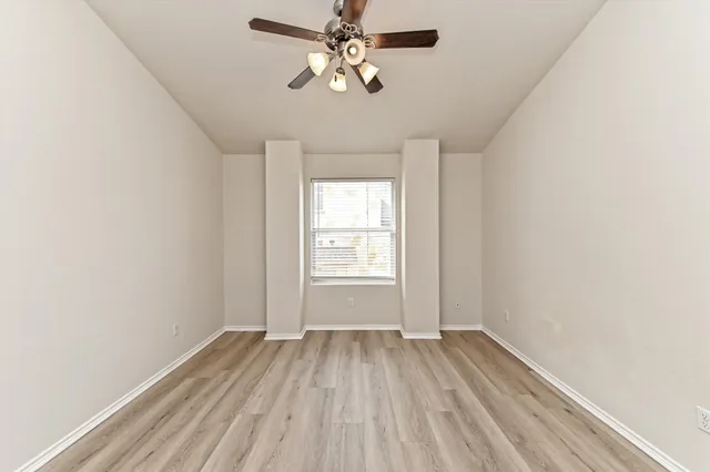a view of a room with wooden floor a ceiling fan and windows