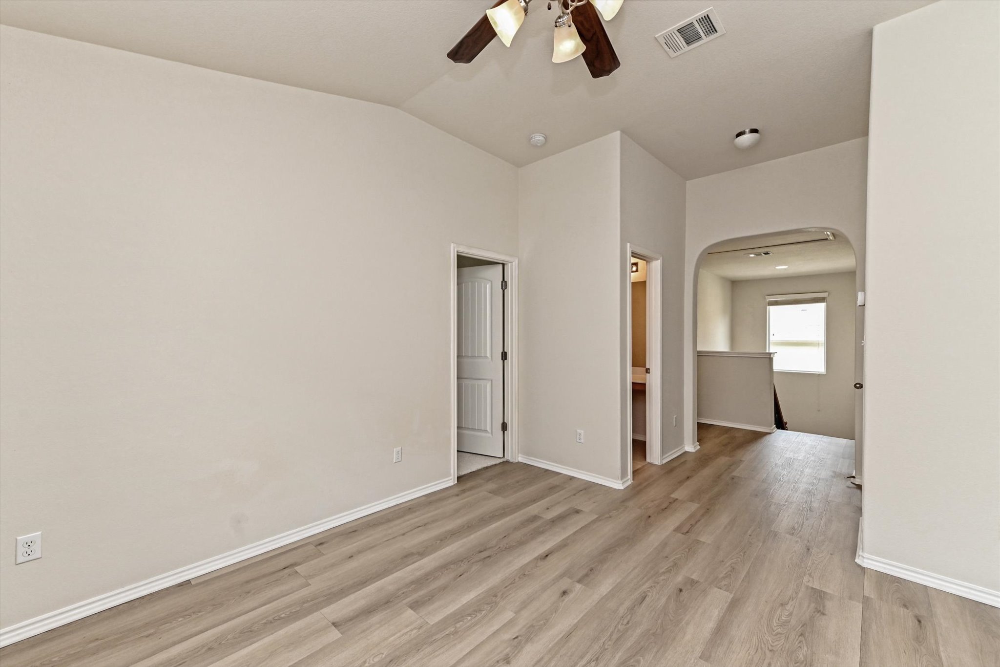 31 Stone Terrace Drive Austin, TX 78734 - Photo 16 of 29 Empty room featuring arched walkways, a ceiling fan, light wood finished floors, and vaulted ceiling