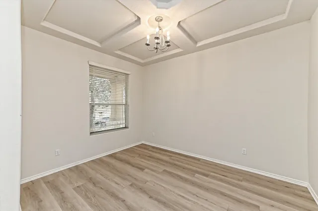an empty room with a chandelier fan and windows