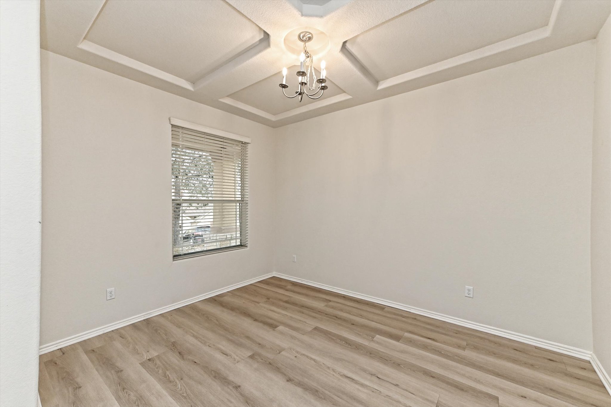31 Stone Terrace Drive Austin, TX 78734 - Photo 4 of 29 Spare room with coffered ceiling, a chandelier, and light wood-style floors