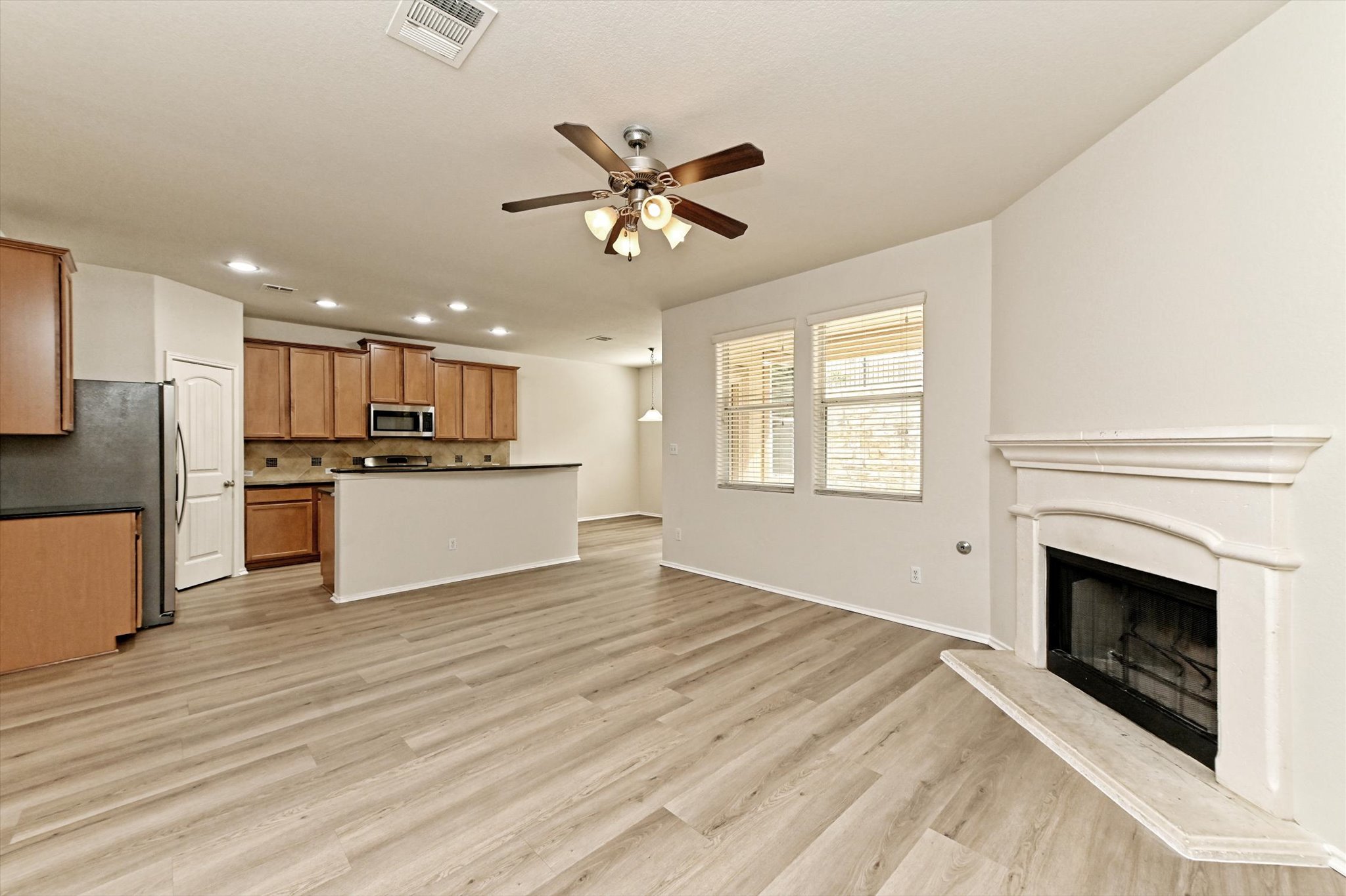 31 Stone Terrace Drive Austin, TX 78734 - Photo 8 of 29 Unfurnished living room with ceiling fan, recessed lighting, a fireplace with raised hearth, and light wood-type flooring