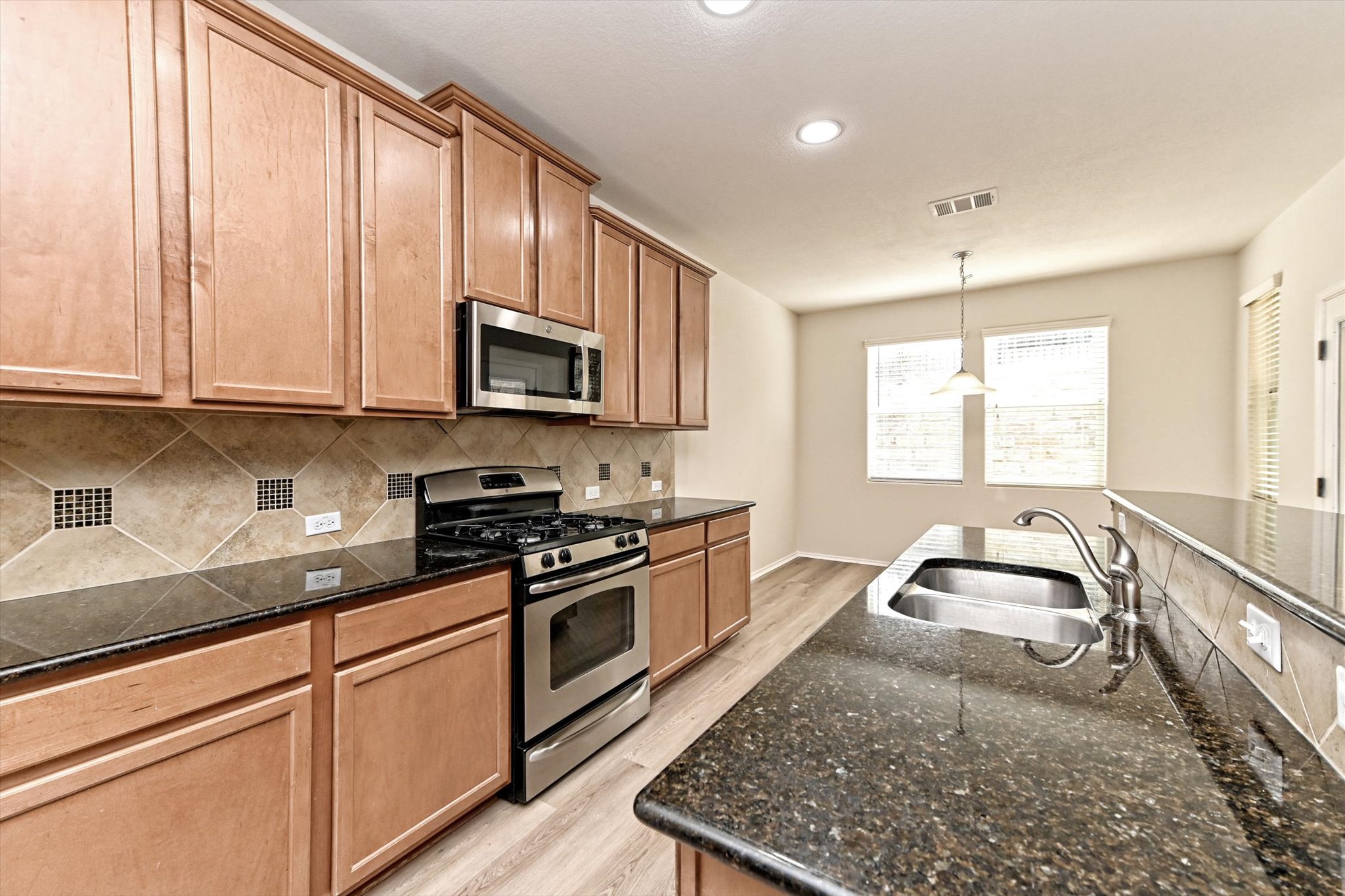 31 Stone Terrace Drive Austin, TX 78734 - Photo 10 of 29 Kitchen with stainless steel appliances, dark stone counters, pendant lighting, light wood finished floors, and decorative backsplash