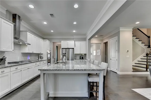 a kitchen with granite countertop kitchen island stainless steel appliances sink stove dining table and chairs