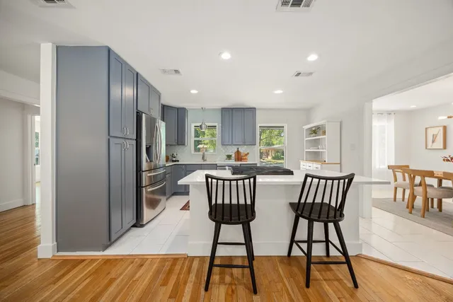 a kitchen with stainless steel appliances granite countertop a dining table chairs and granite counter tops