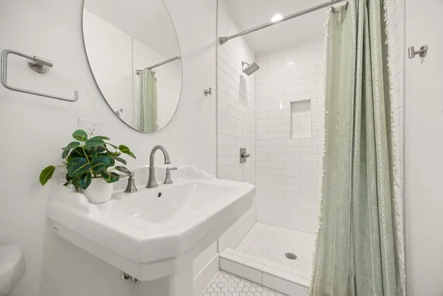 a bathroom with a sink a mirror a glass door a shower and a mirror