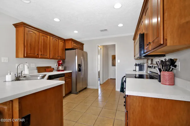 a kitchen with stainless steel appliances granite countertop a sink refrigerator and cabinets