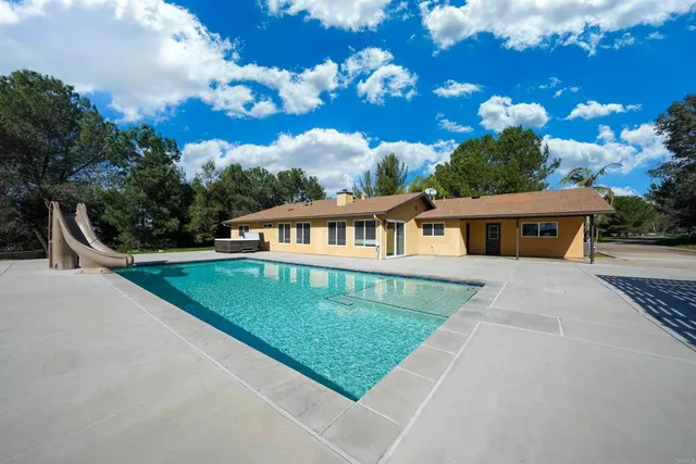 a large kitchen with a large counter top space a sink stainless steel appliances and cabinets