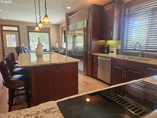 a kitchen with kitchen island granite countertop a sink cabinets and wooden floor
