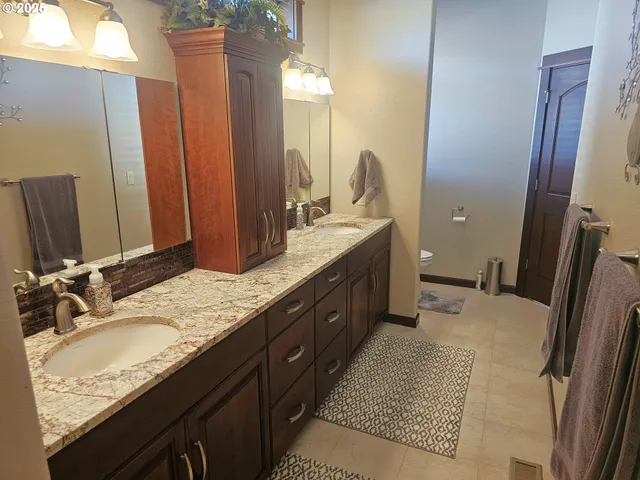 a bathroom with a granite countertop double vanity sink and mirror