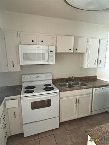 a white stove top oven sitting inside of a kitchen