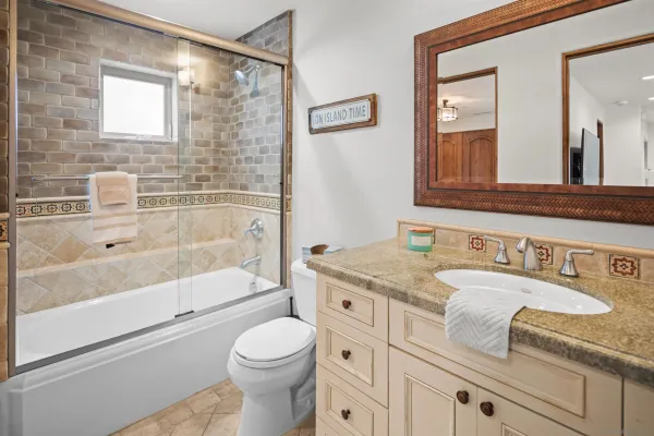a bathroom with a granite countertop sink a toilet a mirror a bathtub and shower