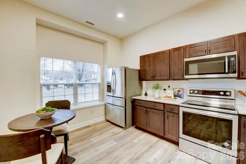 a kitchen with stainless steel appliances a stove a sink a refrigerator white cabinets and wooden floor