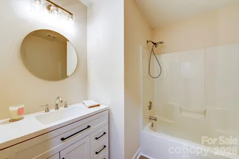 a bathroom with a granite countertop sink a mirror and a bathtub