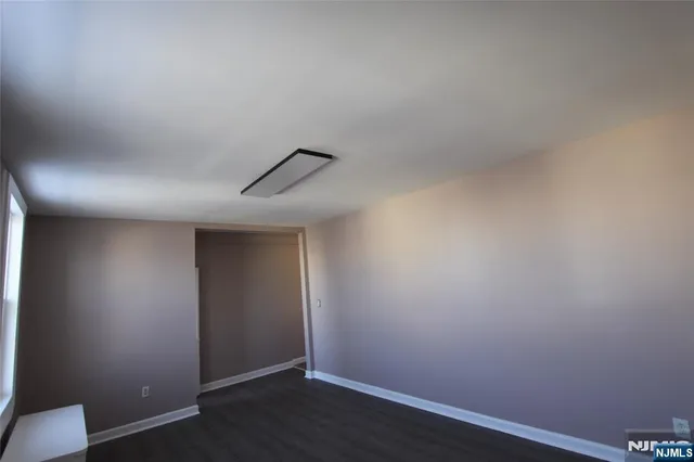 an empty room with wooden floor and ceiling fan