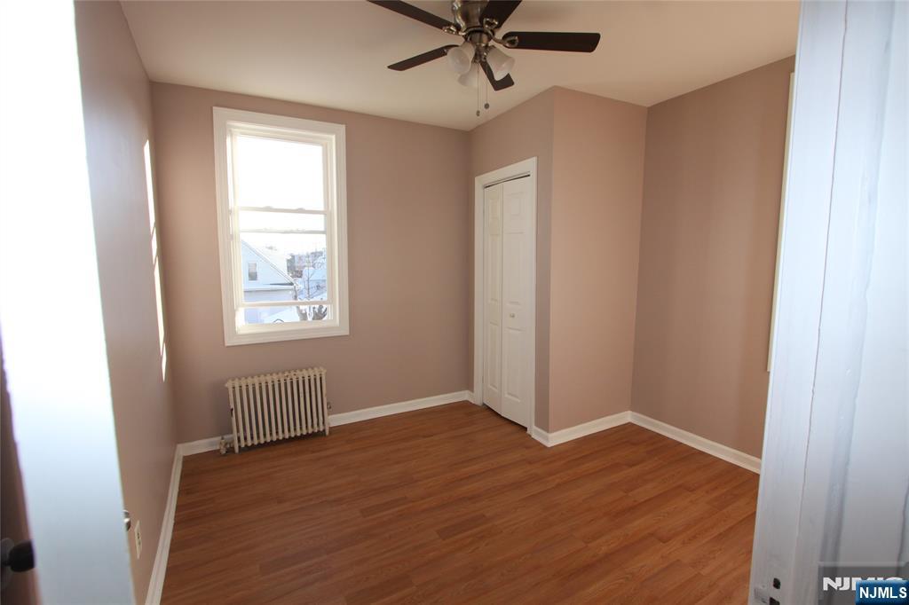 10 Orchard Street, Unit 2 Elmwood Park, NJ 07407 - Photo 3 of 12 an empty room with wooden floor windows and fan