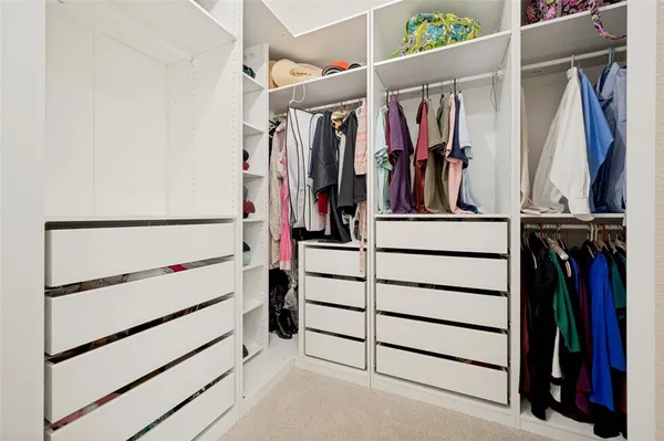a view of walk in closet with clothes and shoes