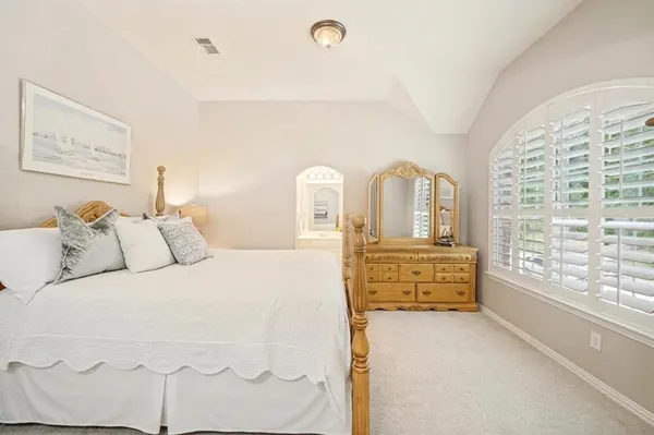 a bedroom with a balcony a bed and a dresser next to a window