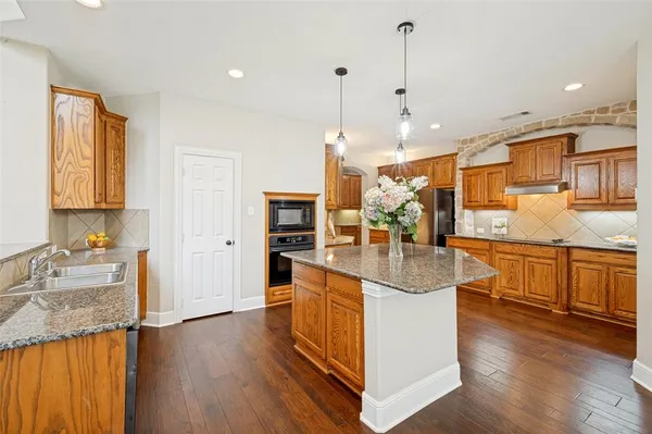a kitchen with stainless steel appliances granite countertop a sink a stove and a wooden floors