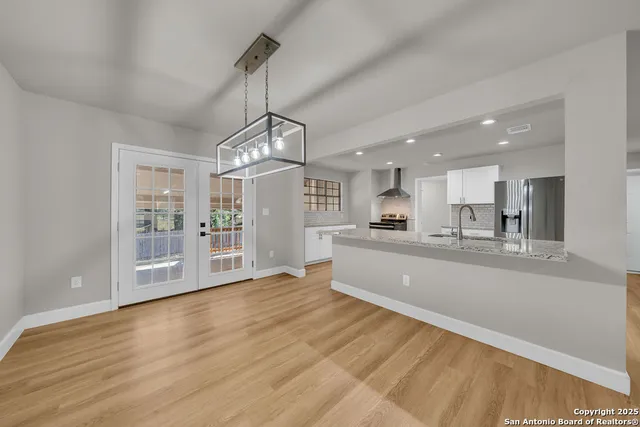 a large kitchen with stainless steel appliances granite countertop a large counter top a sink and a chandelier