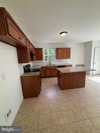 a kitchen with granite countertop a sink a counter top space and cabinets