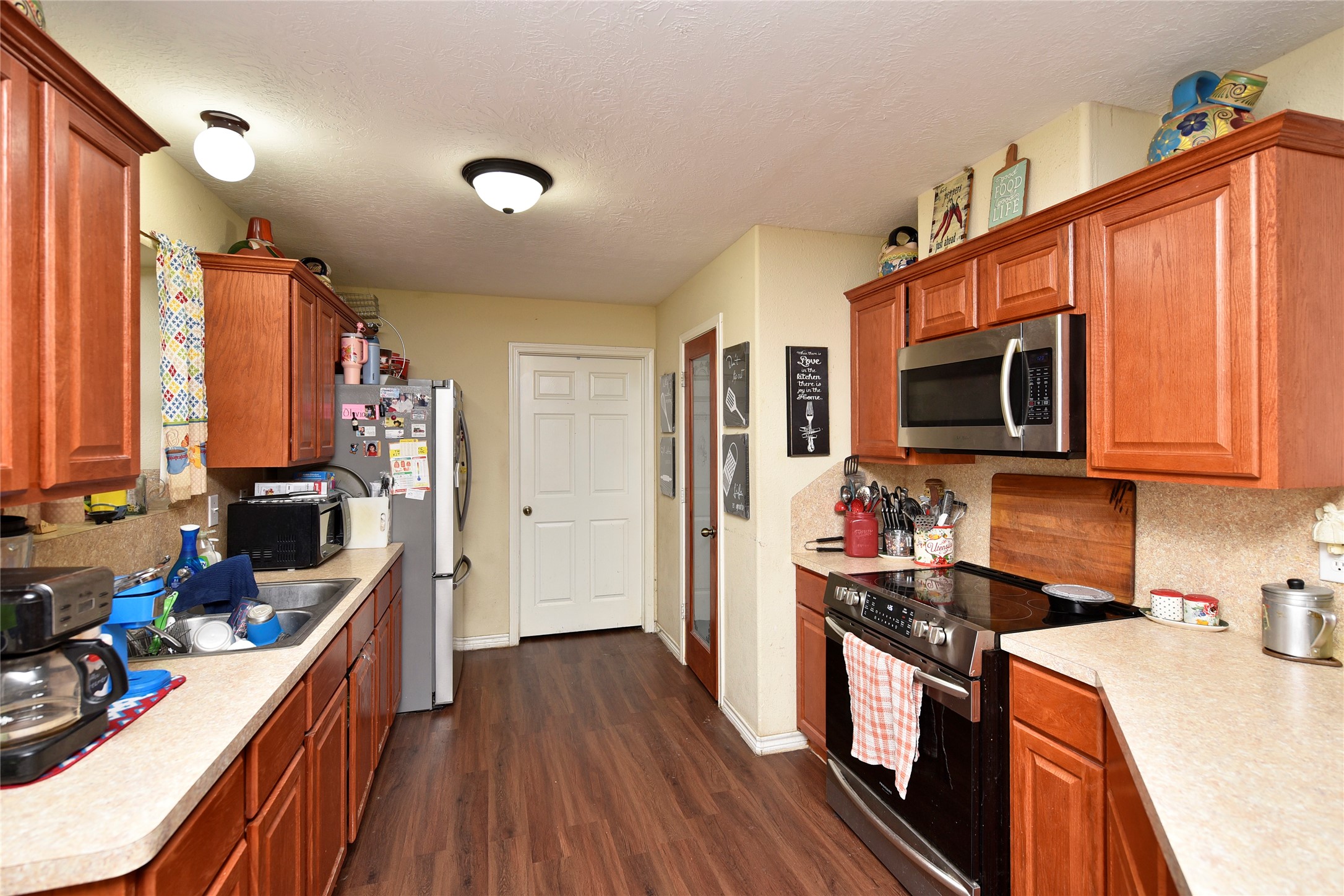 6018 FM 360 Road Needville, TX 77461 - Photo 22 of 50 a kitchen with stainless steel appliances a stove top oven a sink dishwasher and a refrigerator with wooden floor