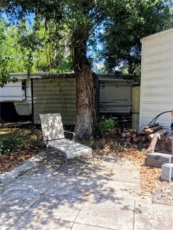 a view of a backyard with chairs and potted plants